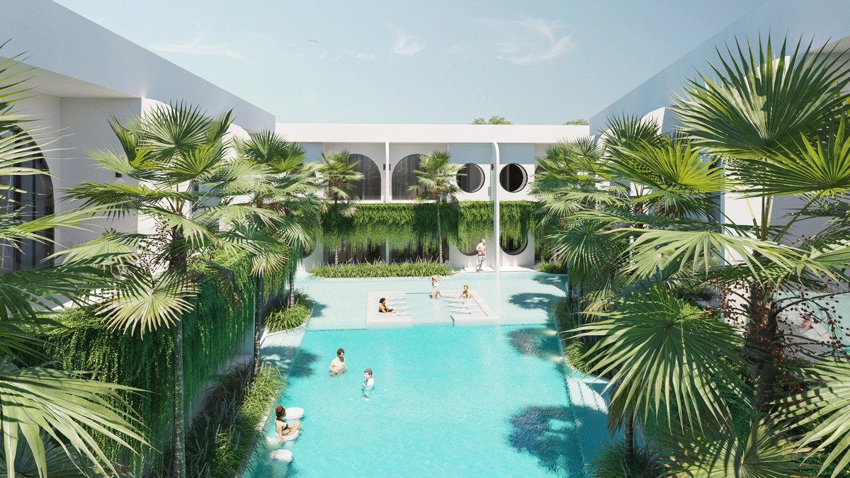 Lagoon pool in a planted courtyard at Cora Beach Resort, with palms at the water line and a two-storey arched colonnade behind