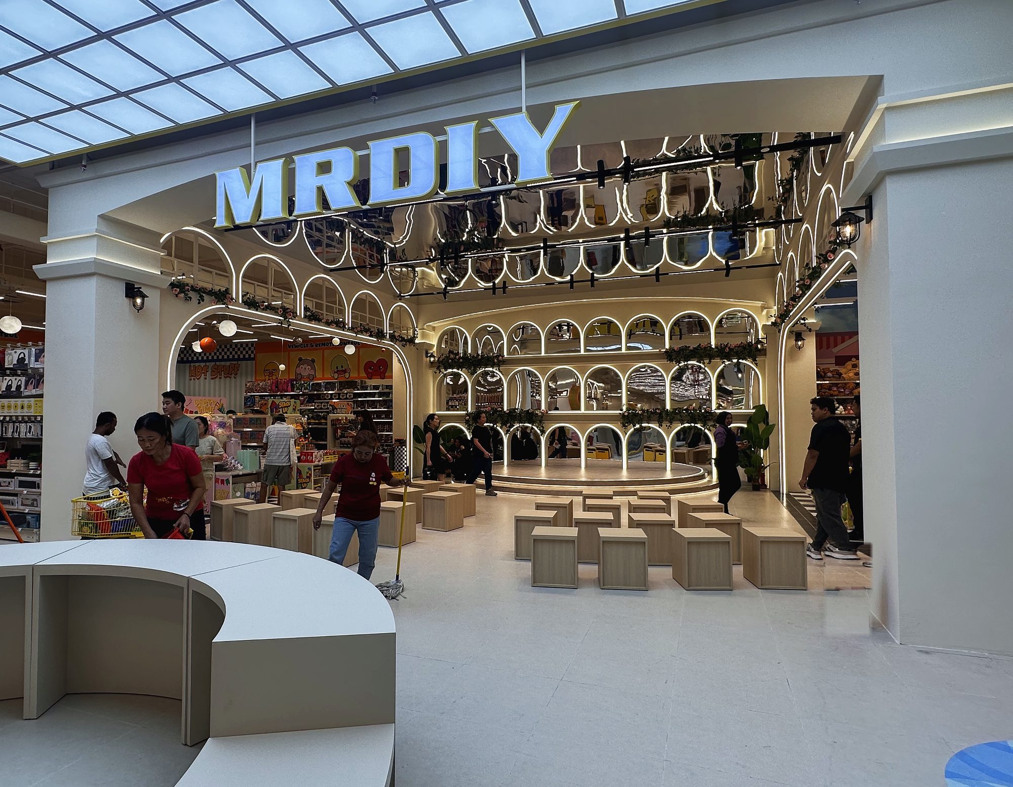 The arched, back-lit display wall and central stage at MR D.I.Y Plus, The Mines